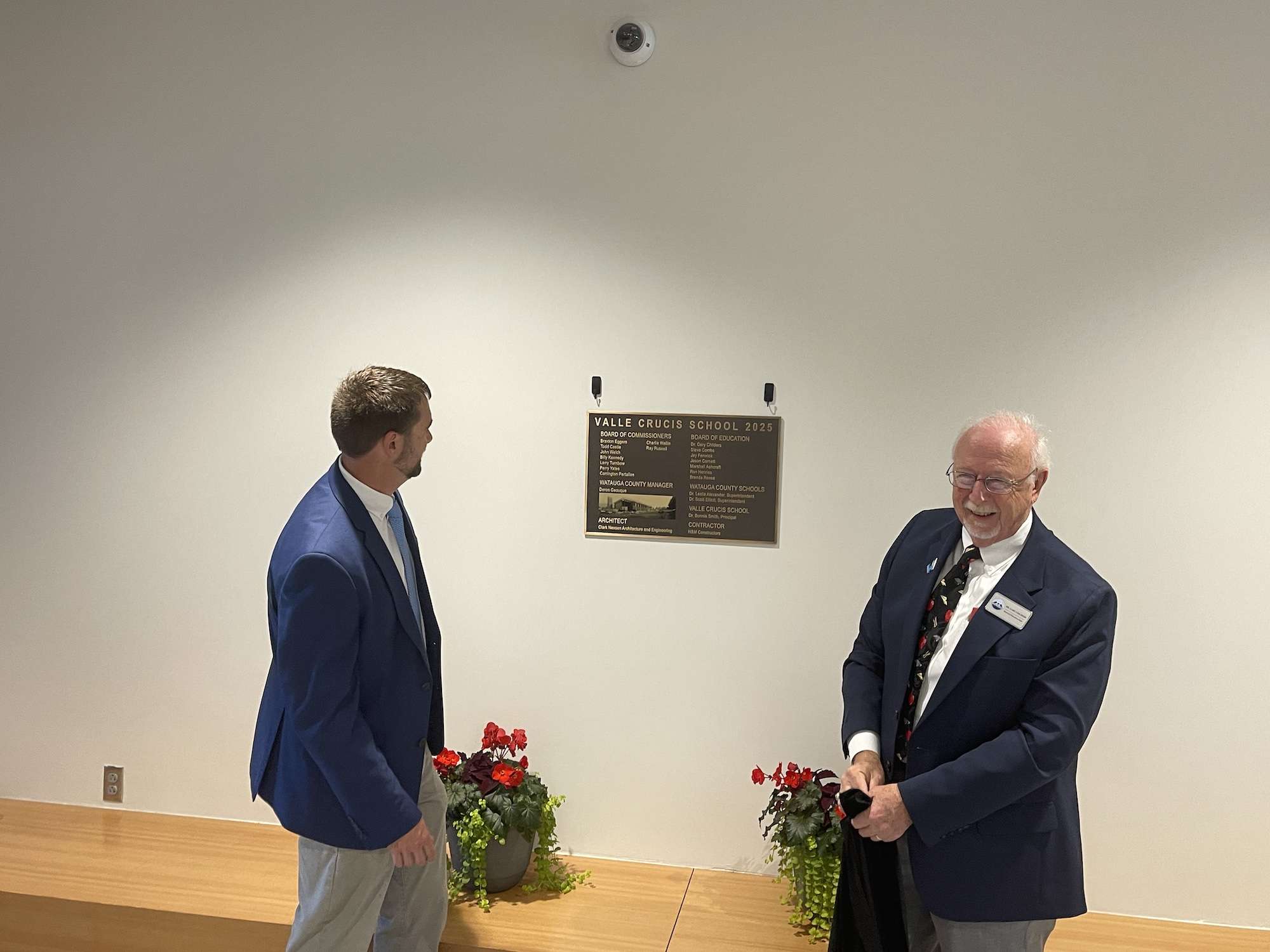 Watauga County Commissioners Chair Braxton Eggers and WCS Board of Education Chair Dr. Gary Childers stand by the covered dedication plaque inside Valle Crucis School.