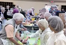 Volunteers in hairnets pack meals at long tables at First Baptist Church of Newland during the Hope for the High Country event on June 20, 2026, benefiting Avery County families recovering from Hurricane Helene.