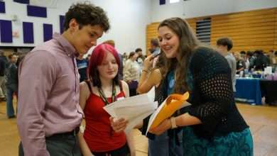 Ashe County GEAR UP Coordinator Hope Gambill reviews resumes with students at a career fair at Ashe County High School