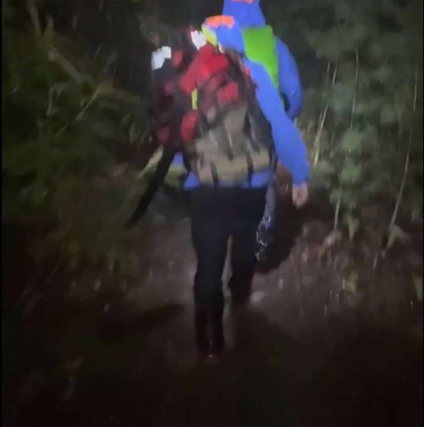 A hiker walks a trail at night during the rescue effort