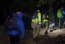 Rescuers walk with hikers and a dog at night