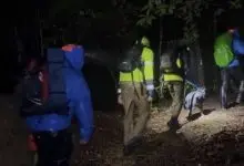 Rescuers walk with hikers and a dog at night