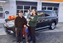 A family stands with their vehicle in front of the Working Wheels shop