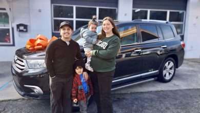 A family stands with their vehicle in front of the Working Wheels shop