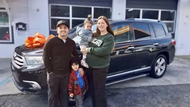 A family stands with their vehicle in front of the Working Wheels shop
